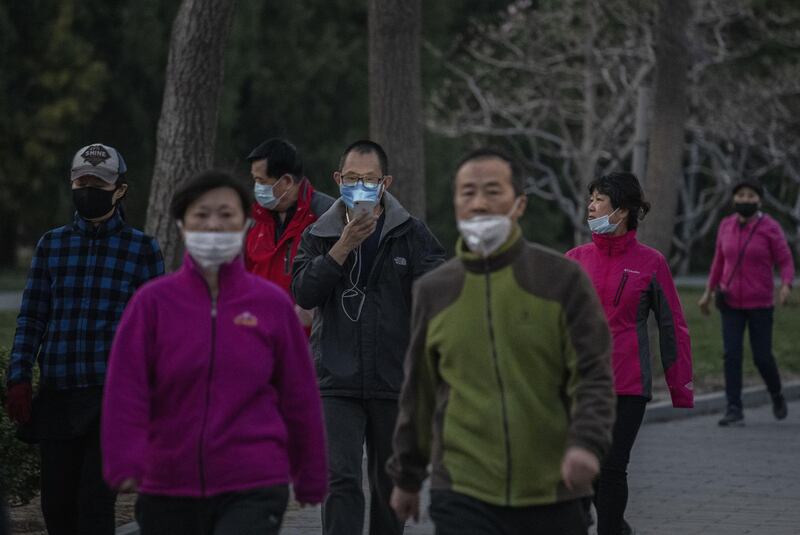 People wear protective masks as they walk at Ritan Park in Beijing, China. Getty Images