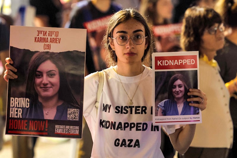 A woman holds placards identifying one of the Israeli hostages held by Hamas during a demonstration in Tel Aviv. AFP
