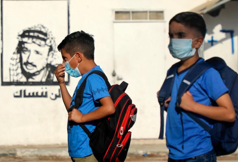 Palestinian students, wearing protective face masks, gather in the courtyard, next to a graffiti of late leader Yasser Arafat, on the first day of school in the village of Salem east of Nablus in the occupied West Bank on September 6, 2020, during the coronavirus pandemic. (Photo by JAAFAR ASHTIYEH / AFP)