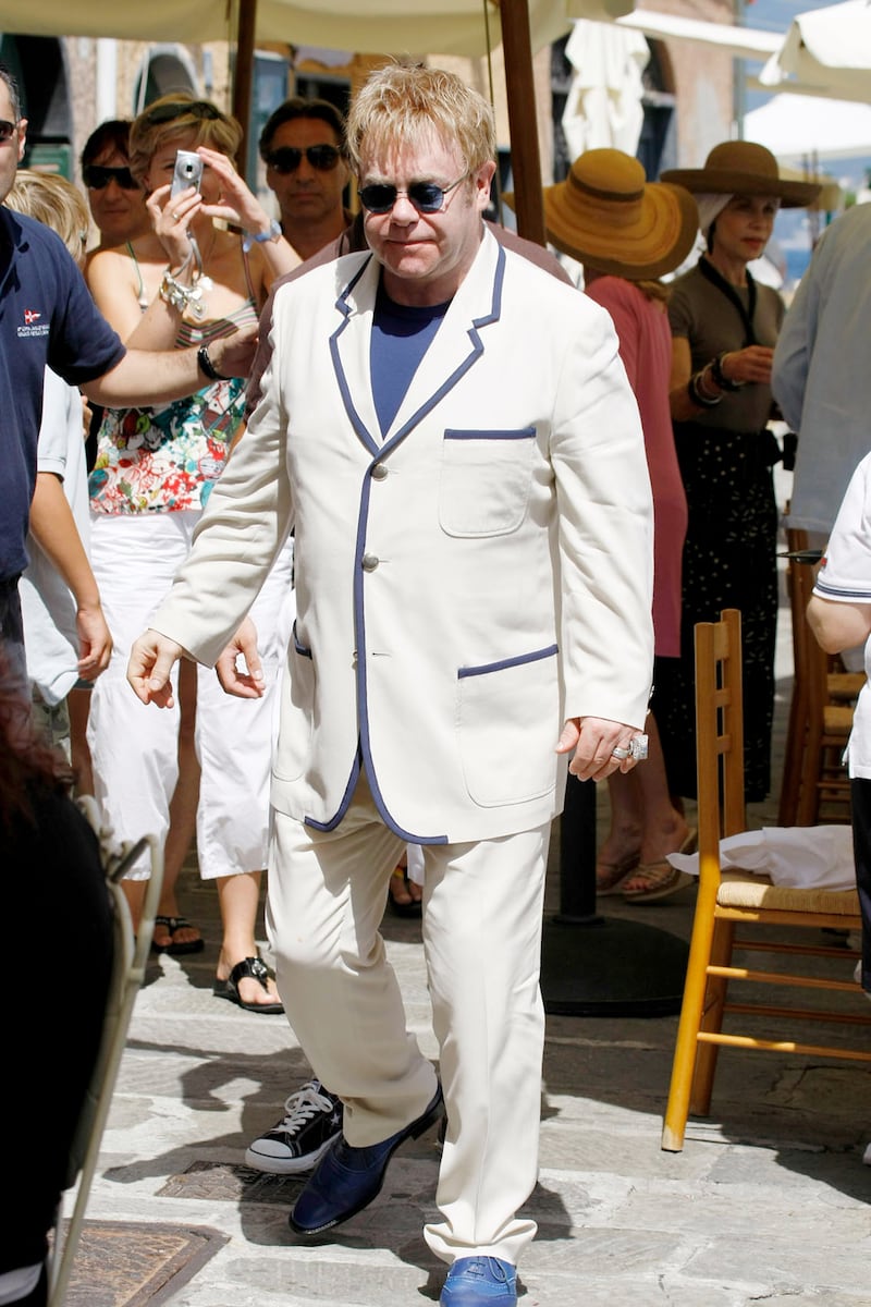 Elton John, wearing a cream suit with blue edging, wanders through Portofino, Italy on August 12, 2008. Getty Images