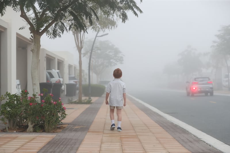 A young boy walks to his school bus on a foggy day in Dubai. Chris Whiteoak / The National