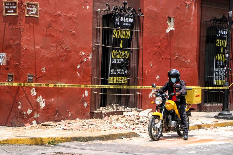 A motorcyclist rides past security tape alerting of a damaged building after a quake in Oaxaca, Mexico. AFP