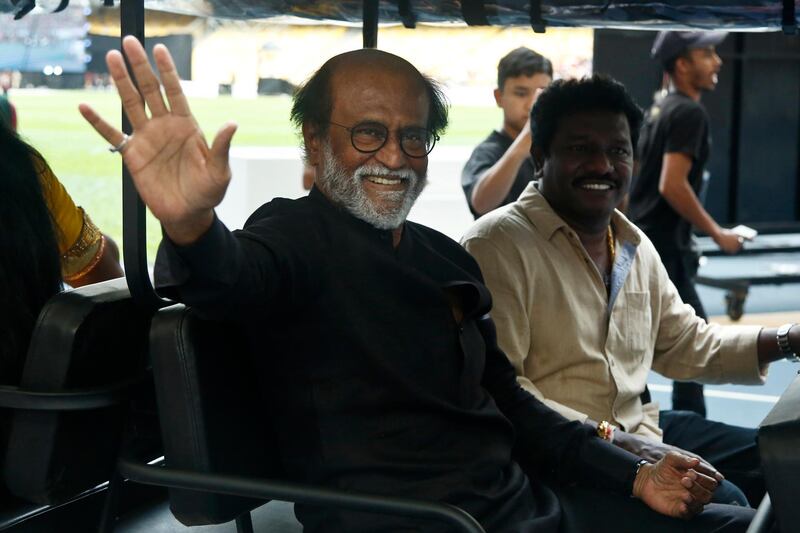 Indian movie superstar Rajinikanth, left, waves to his fans as he arrives at an event in Kuala Lumpur, Malaysia, Saturday, Jan. 6, 2018. (AP Photo/Sadiq Asyraf)
