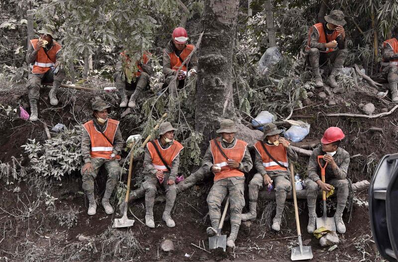 Soldiers take a break during the search for victims of the Fuego Volcano in the ash-covered village of San Miguel Los Lotes south-west of Guatemala City. Johan Ordonez / AFP