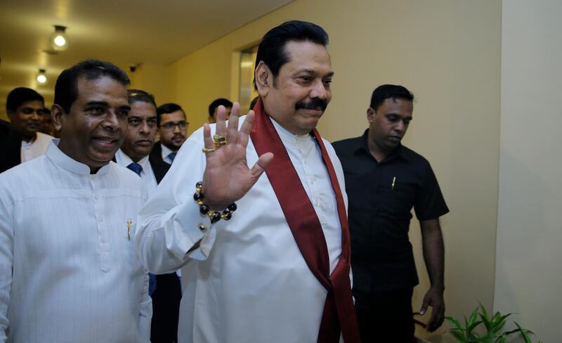 Sri Lanka's disputed Prime Minister Mahinda Rajapaksa, gestures as he arrives for a meeting with his supporting law makers at the parliamentary complex in Colombo, Sri Lanka, Thursday, Nov. 29, 2018. Sri Lankan lawmakers have approved a motion barring Rajapaksa from using state funds after he was defeated in a no confidence vote. (AP Photo/Eranga Jayawardena)