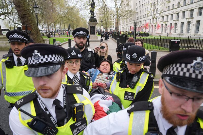 A protester is detained after members of Youth Demand throw red paint over the Ministry of Defence building in London. AP