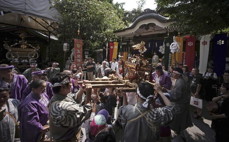 Residents and children from a local neighborhood carry a portable shrine to celebrate their festival at Torigoe Shrine in Tokyo. Eugene Hoshiko / AP Photo