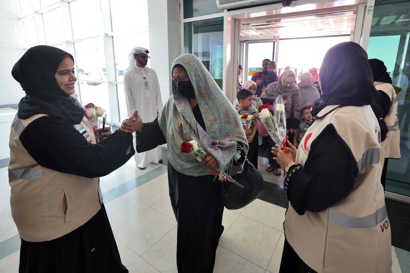 Emirates Red Crescent officials hand out gifts of flowers as the travellers from Sudan arrive in the UAE. AFP