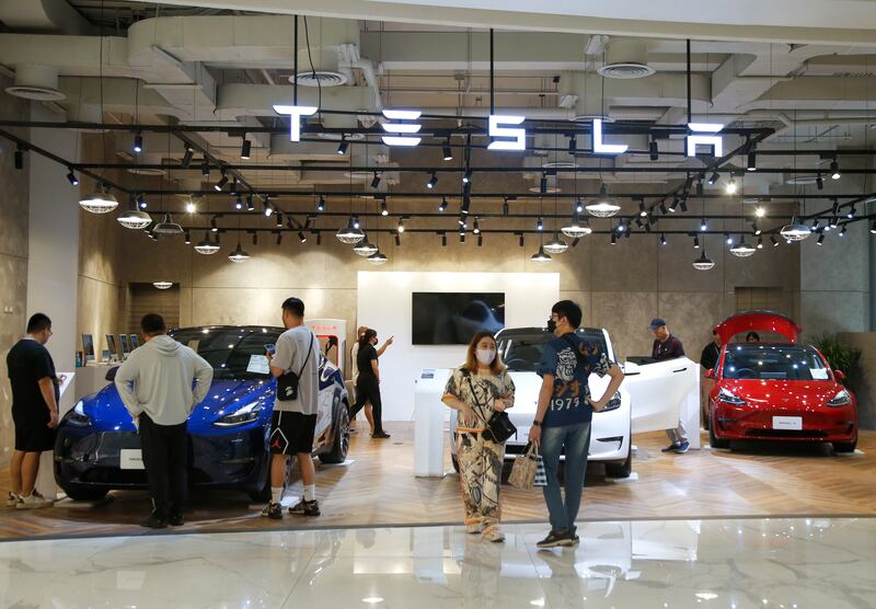Shoppers at a mall in Bangkok inspect Tesla electric cars displayed at a pop-up roadshow. EPA