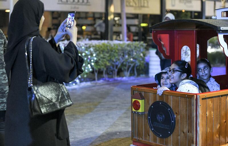 Abu Dhabi, United Arab Emirates - Mother takes photos of her children before they head out on the train ride at the Winter Wonderland event on the Galleria Mall promenade. Khushnum Bhandari for The National