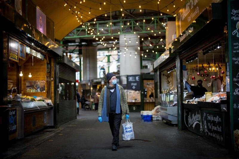 A customer wears a face mask because of the coronavirus pandemic as they shop at Borough Market in London on January 12, 2021. Borough market, an open-air market popular with tourists and Londoners alike, has required customers and stall-holders to wear masks since January 11 as a measure  to keep the market open and Covid-safe as the UK continues to be hard hit by a second wave in the coronavirus pandemic. / AFP / Tolga Akmen
