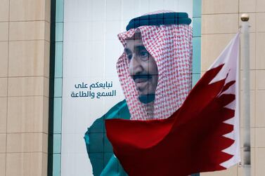 A Qatari flag flies in front of a portrait of Saudi King Salman in Riyadh ahead of the 40th GCC summit on December 10, 2019. AP Photo