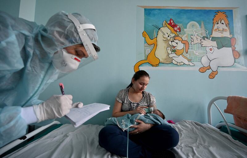 A mother holds an oxygen mask over the face of her baby suffering from Covid-19  in Kiev, Ukraine. AFP