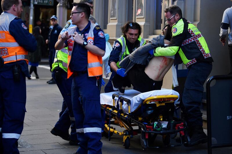 A woman is carried by paramedics, as police officers investigate a scene following reports of a stabbing in Sydney, Australia.  REUTERS