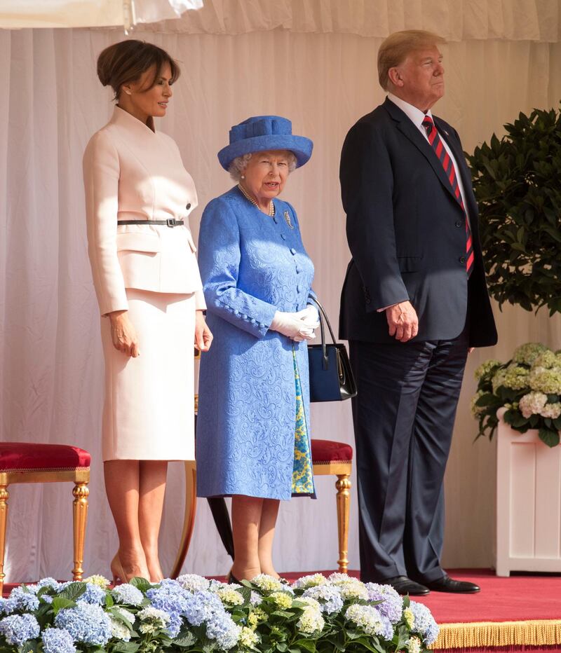 WINDSOR, ENGLAND - JULY 13:  U.S. President Donald Trump and first lady Melania Trump stand with Britain's Queen Elizabeth II on the dais in the Quadrangle of Windsor Castle on July 13, 2018 in Windsor, England.  Her Majesty welcomed the President and Mrs Trump at the dais in the Quadrangle of the Castle. A Guard of Honour, formed of the Coldstream Guards, gave a Royal Salute and the US National Anthem was played. The Queen and the President inspected the Guard of Honour before watching the military march past. The President and First Lady then joined Her Majesty for tea at the Castle.    (Photo by Richard Pohle  - WPA Pool/Getty Images)