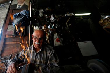 A Syrian man works in his metal workshop beneath a portrait of Syrian President Bashar al-Assad in old Damascus, on June 16, 2020. The Caesar Syria Civilian Protection Act of 2019, a US law that aims to sanction any person who assists the Syrian government or contributes to the country's reconstruction, is to come into force on June 17. / AFP / LOUAI BESHARA