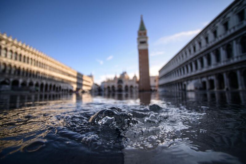 Water bubbles up from a manhole on the flooded St Mark's Square on November 14, 2019 in Venice. AFP