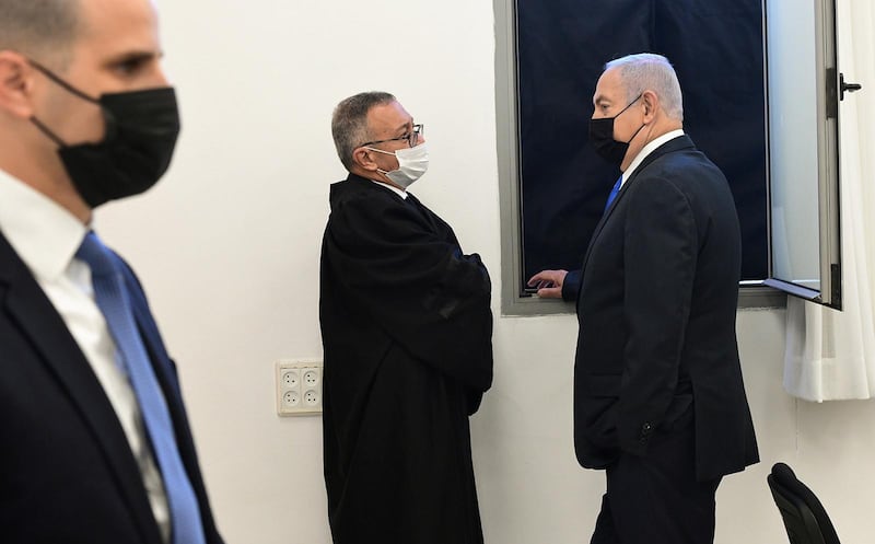 Israeli Prime Minister Benjamin Netanyahu wearing a protective face mask, speaks to a member from his legal team before the start of a hearing in his corruption trial at Jerusalem's District Court.  Reuters