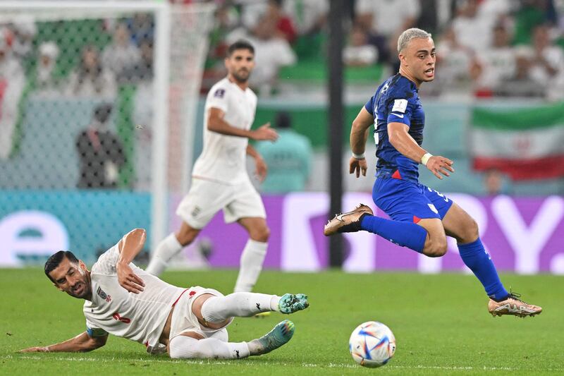 Iran's Ehsan Hajsafi fights for the ball with USA defender Sergino Dest. AFP