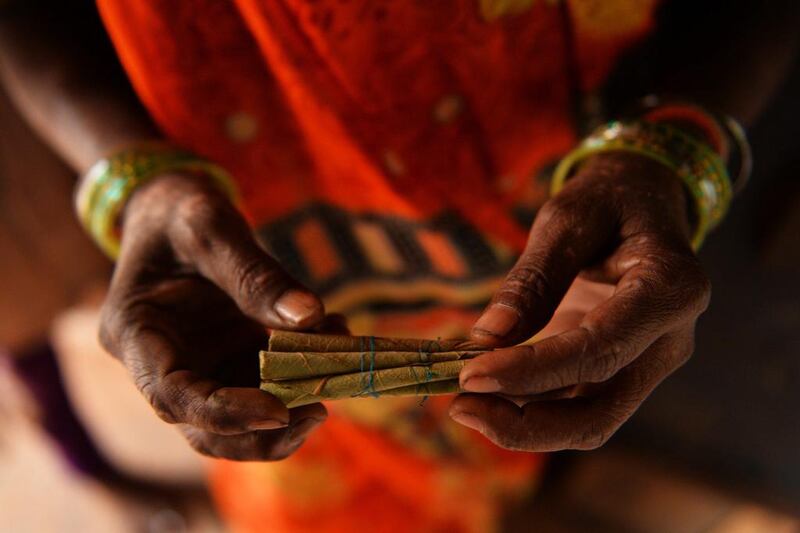 A female labourer shows a bundle of bidis which she rolled.