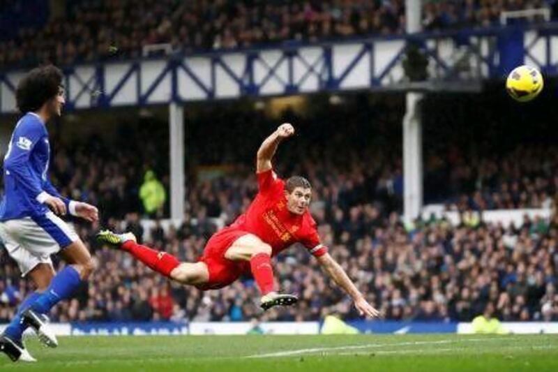 Liverpool's Steven Gerrard, centre, fires a shot goalwards as Everton's Marouane Fellaini watches.