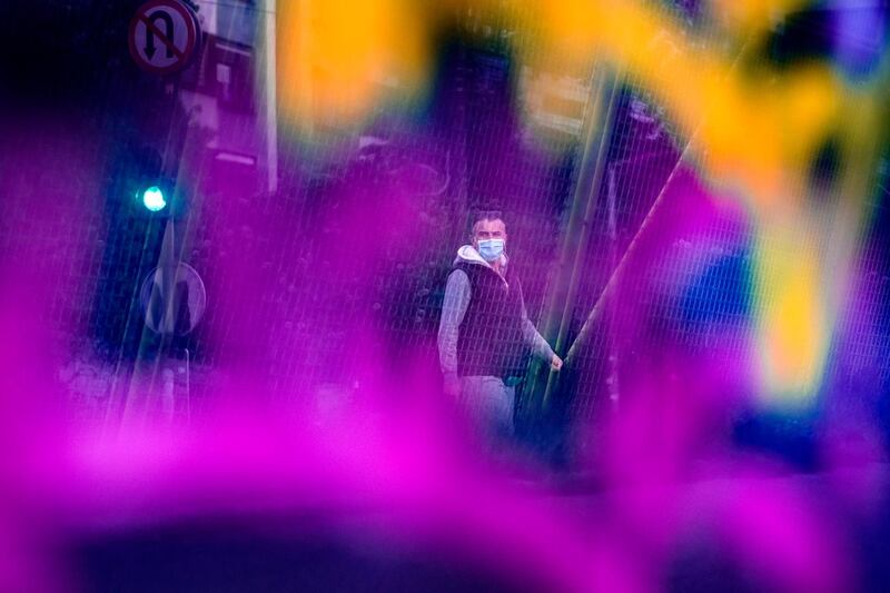 Seen through a bridge glass panel covered in graffiti a man wearing a face mask walks in Sarajevo, Bosnia. AP Photo