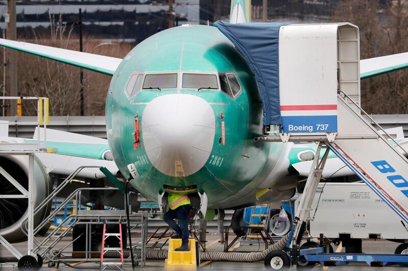 FILE - In this Dec. 16, 2019, file photo a worker looks up underneath a Boeing 737 MAX jet in Renton, Wash. Boeing doesn't expect federal regulators to approve its changes to the grounded 737 Max until this summer, according to two people familiar with the matter. (AP Photo/Elaine Thompson, File)