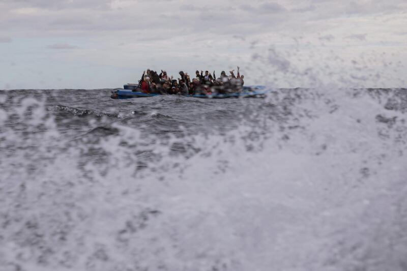 Men from Morocco and Bangladesh react on an overcrowded wooden boat, as aid workers of the Spanish NGO Open Arms approach them in the Mediterranean Sea, international waters, off the Libyan coast. AP