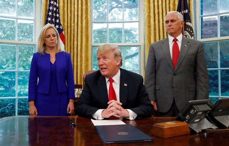 U.S. President Donald Trump speaks to reporters about signing an executive order on immigration policy with DHS Secretary Kirstjen Nielsen and Vice President Mike Pence at his sides in the Oval Office of the White House in Washington, U.S., June 20, 2018.  REUTERS/Leah Milllis     TPX IMAGES OF THE DAY