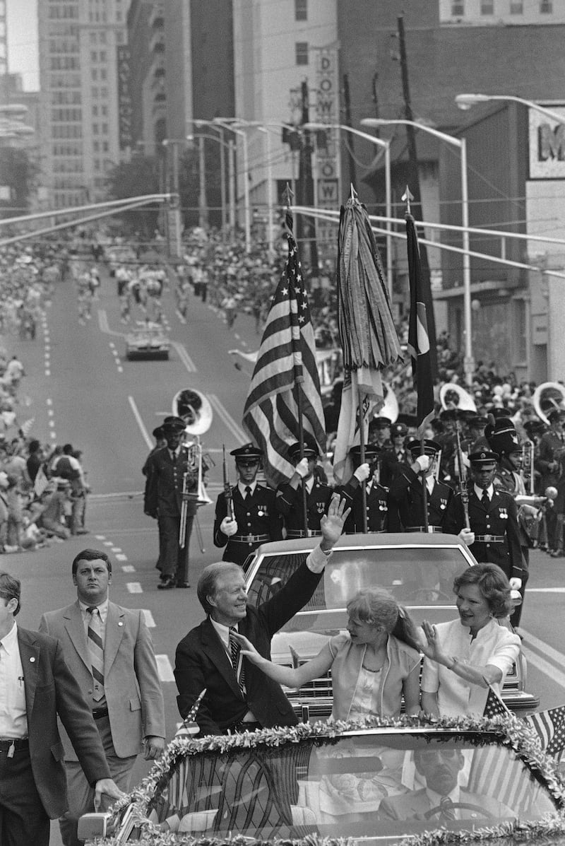 In this July 4, 1981 photo, US President Jimmy Carter, his wife Rosalynn Carter, right, and daughter Amy Carter, wave to the crowd along Peachtree Street as they lead a parade through the streets in Atlanta. AP Photo