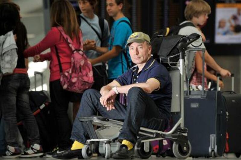 British novelist and journalist Tony Parsons sits on a luggage trolley as he poses for pictures in London Heathrow Airport's Terminal 5 on August 3, 2011. Parsons starts work wednesday as writer in residence at Heathrow airport, in search of inspiration for his collection of short stories which will be entitled 'Departures: Seven Stories from Heathrow.' AFP PHOTO / BEN STANSALL
 *** Local Caption ***  544587-01-08.jpg