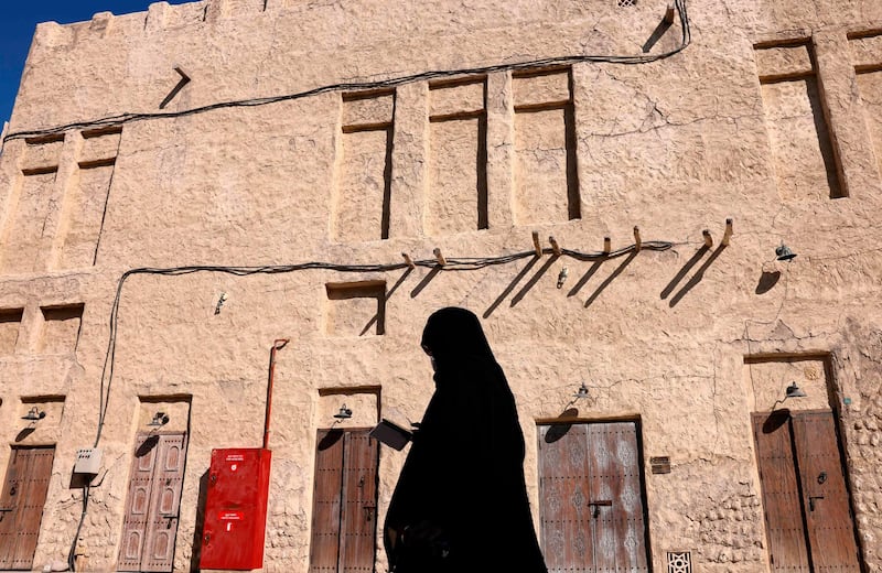 A woman walks in front of a traditional house in the neighborhood of Al Fahidi. AFP