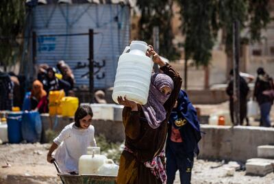 A woman in the Syrian city of Hasaka carries a container of water provided by Unicef after supply from the Allouk station was disrupted in   July 2021. AFP
