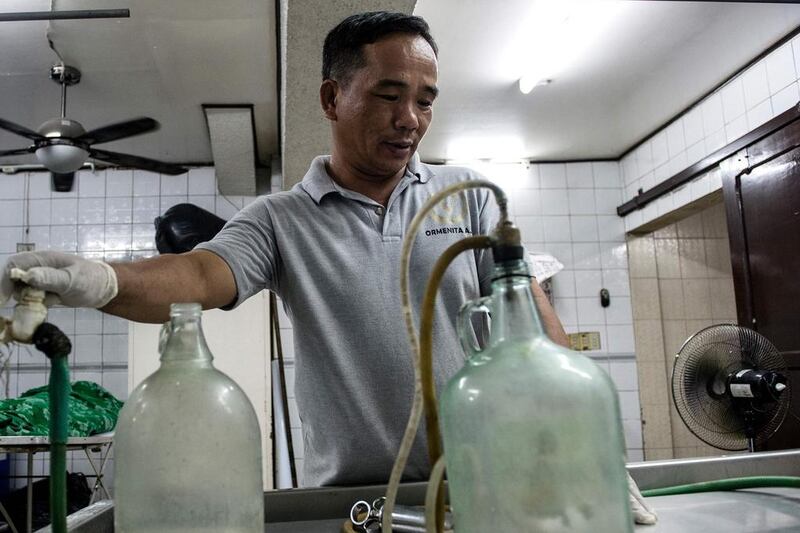 Funeral home worker Alejandro Ormeneta prepares embalming instruments before operating on a body inside the morgue of the Veronica Memorial Chapel in Manila on October 30, 2016. Noel Celis/AFP 

