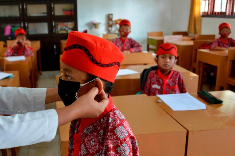 A teacher puts a face mask on a student at an elementary school in Banda Aceh, Indonesia. AFP