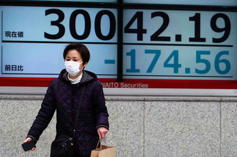 A woman wearing a protective mask walks in front of an electronic stock board showing Japan's Nikkei 225 index at a securities firm Friday, March 19, 2021, in Tokyo. Asian stock markets followed Wall Street lower on Friday after rising U.S. bond yields pulled stocks lower, dampening enthusiasm driven by the Federal Reserve's promise of low interest rates. (AP Photo/Eugene Hoshiko)