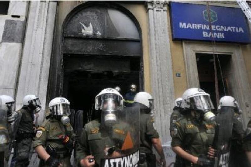 Riot police guard a burnt branch of the Marfin Bank in Athens after a violent demonstration on May 5, 2010. Athens police chiefs mobilized all their forces, including those not on active duty, to restore order on May 5 amid rioting during protests against a government austerity drive. Police were put on a "general state of alert" to deal with the clashes after three people died in the bank that was firebombed on the margins of the demonstrations. AFP PHOTO / Aris Messinis *** Local Caption *** 453639-01-08.jpg