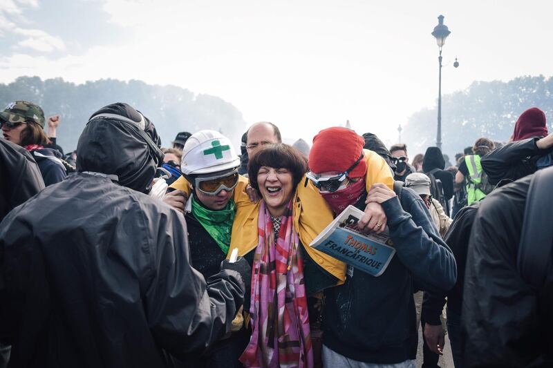 People escort a woman suffering the effects of tear gas on Pont d'Austerlitz. More than 1,000 youths with black jackets and face masks joined the traditional union-led demonstration for worker's rights and attacked police and buildings. AFP/Lucas BARIOULET