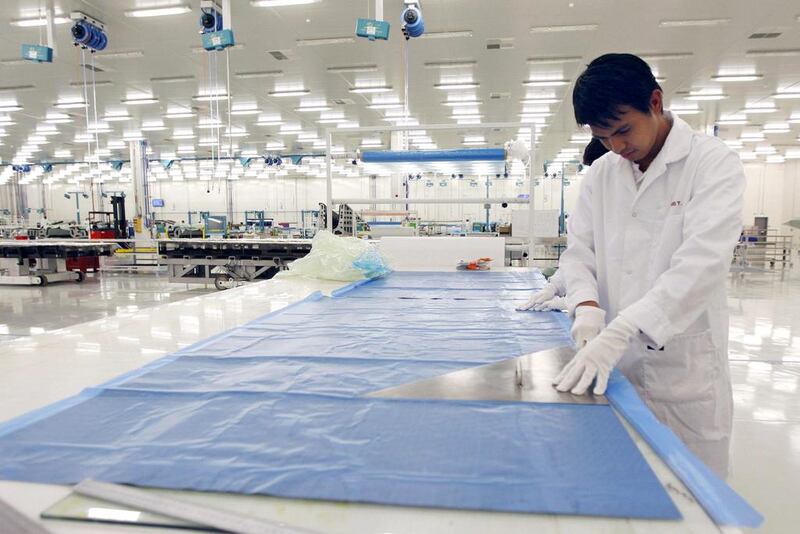 A clean-room operator cuts through a sheet of carbon fiber at STRATA, a composite aerostructures manufacturing plant in Al Ain. Flanked by dunes on an ancient Frankincense route from Yemen to Mesopotamia, the factory is designed to help make lightweight carbon jets that will open up the trade lanes of the future. Jumana El Heloueh / Reuters