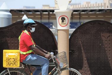 A man on a bike wears a mask to protect himself from Covid-19 in Bur Dubai. Regulations such as mandatory mask-wearing and social distancing rules have helped the UAE curb the spread of the coronavirus. Chris Whiteoak / The National