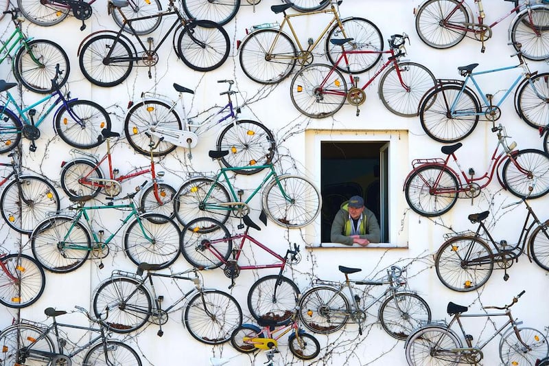 Pet Horstmann, head of the Fahrradhof bike shop in Altlandsberg, eastern Germany, looks out of his house decorated with 210 old bikes. Inside, the shop offers more than 1,000 new bikes for sale. Patrick Pleul / DPA / AFP