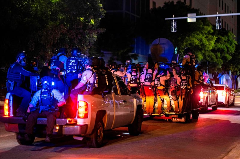 Miami Police officers patrol on the back of pick up trucks to enforce a curfew.  AFP