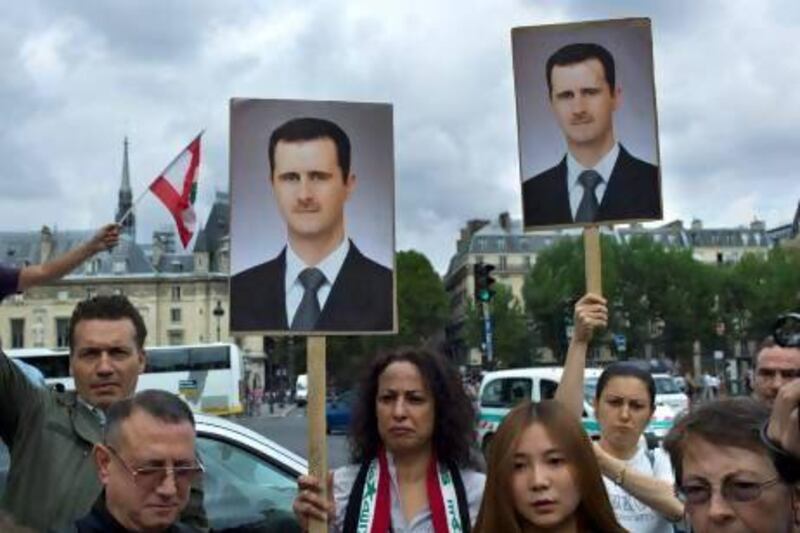 Protesters hold placards showing Syrian president Bashar Al Assad during a demonstration in Paris against French and foreign military involvement in Syria.