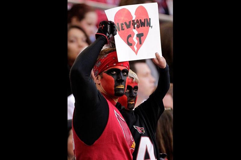 Arizona Cardinals fans hold a sign in memory of the victims of Friday's Sandy Hook Elementary School during a game between the Arizona Cardinals and the Detroit Lions. Matt York / AP Photo