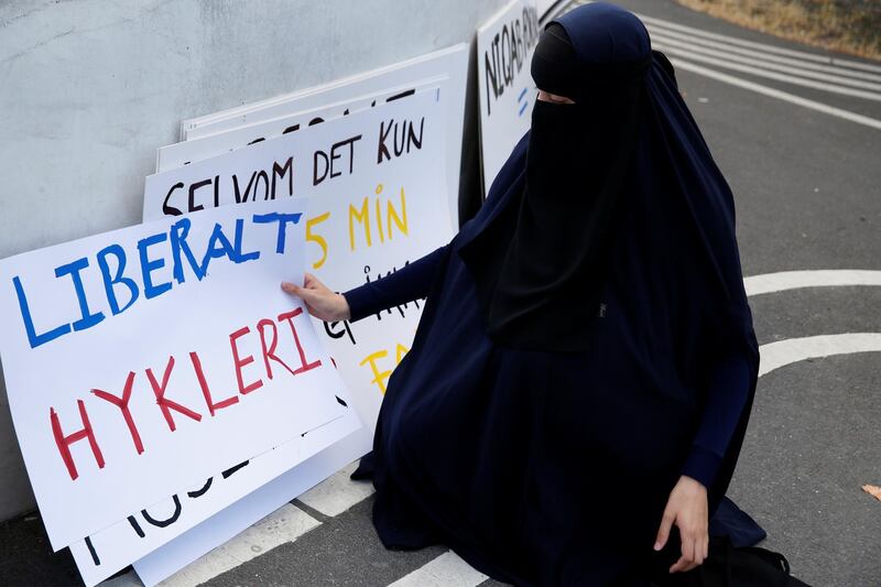A woman in a niqab collects signs at a demonstration against the Danish face veil ban. Reuters
