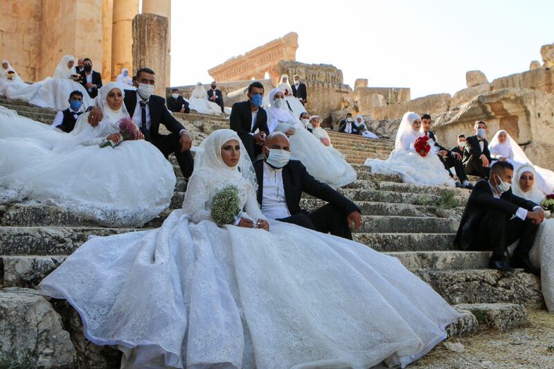 Lebanese couples, wearing protective face masks, sit on the steps during a group wedding at the Temple of Bacchus at the historic site of Baalbek in Lebanon's eastern Bekaa Valley.  AFP