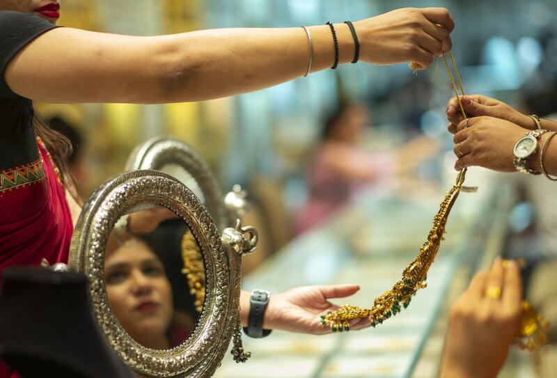 A saleswoman helps a customer try various pieces of jewellery at a shop in New Delhi. Bloomberg