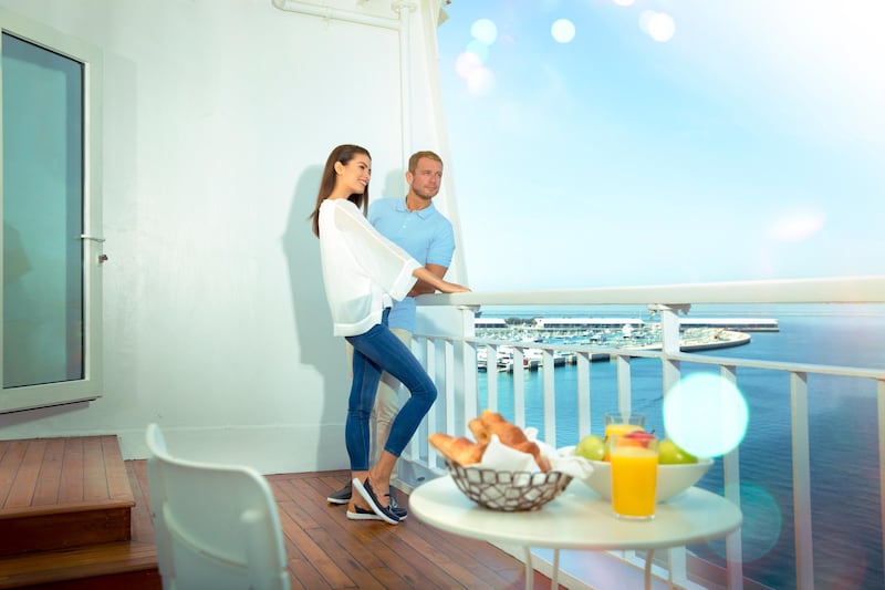 A couple enjoys the balcony on the newly renovated QE2. PCFC Hotels