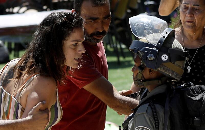 A Palestinian women confronts an Israeli soldier. Palestinian officials said Israel demolished the building because the owner didn't have permits.