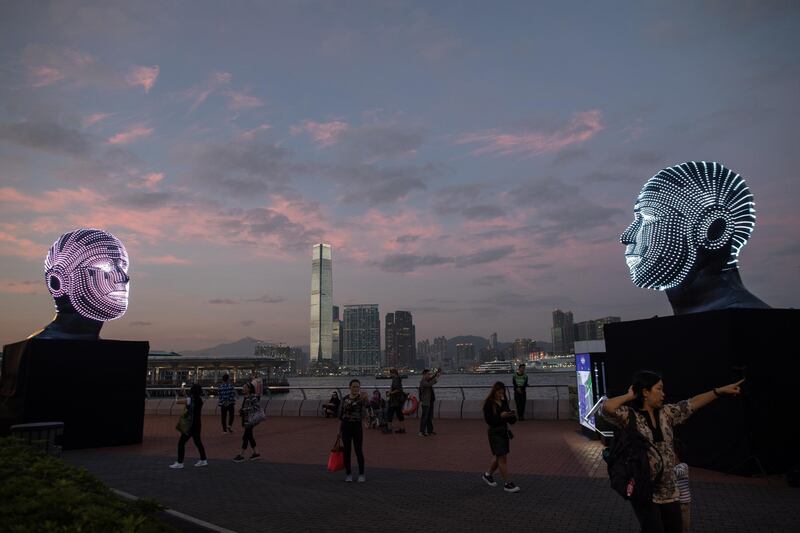 Visitors walk past a light installation by Hungarian artist Viktor Vicsek entitled 'Talking Heads' displayed on the Central harbour waterfront in Hong Kong. EPA